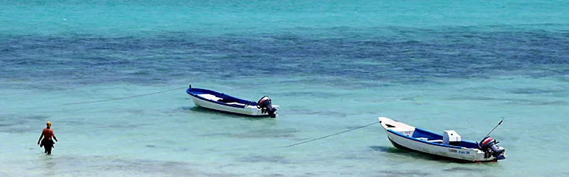 Two boats at anchor, a diver walking