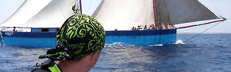 A diver with bandana watches a schooner boat